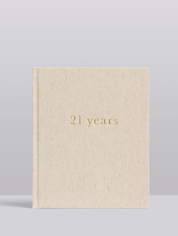 Beige book with '21 years' in gold on a light gray background